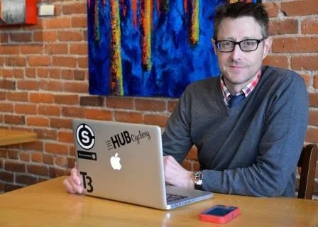 Muž sediaci pri stole s notebookom