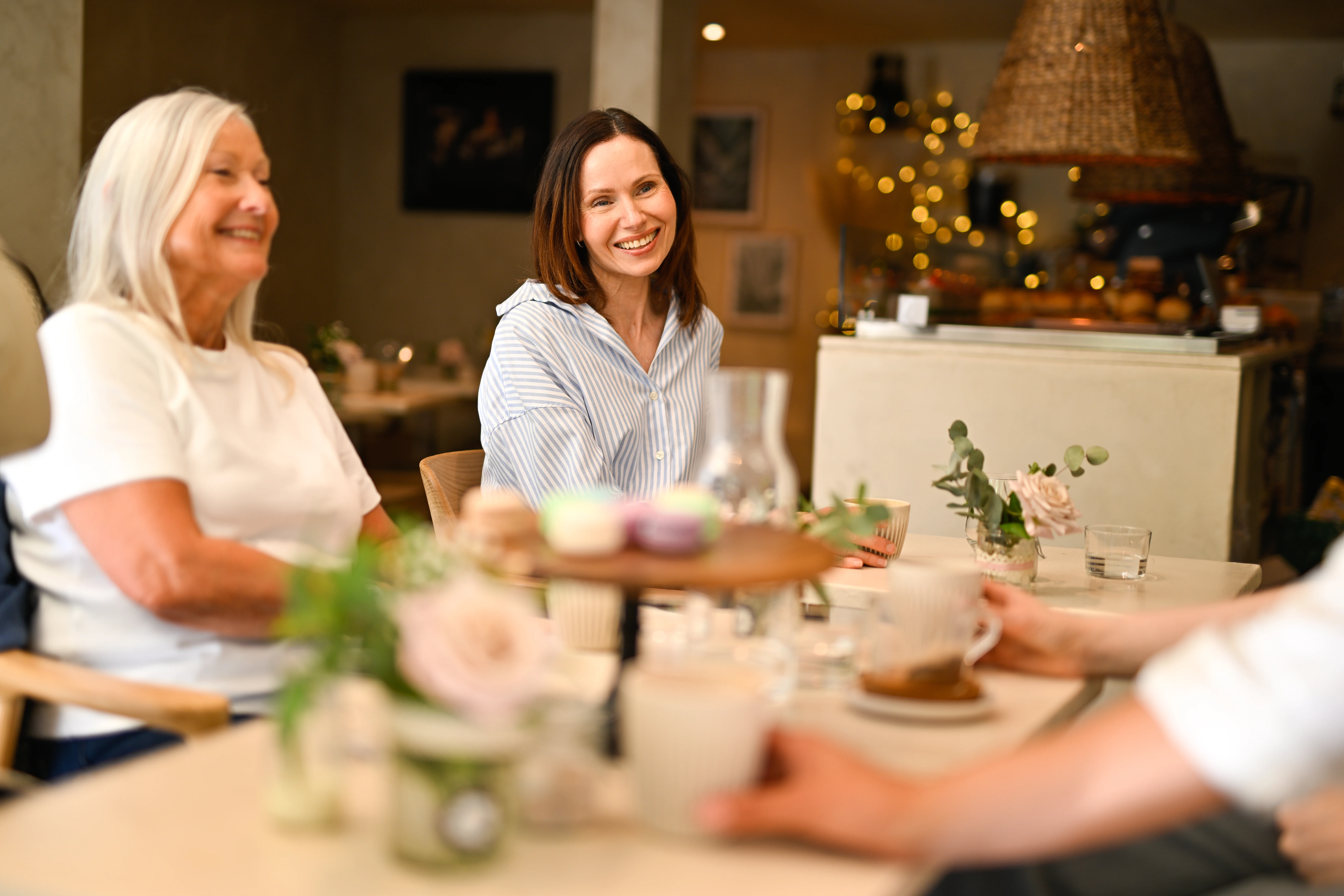 a couple of women sitting at a table with food and drinks