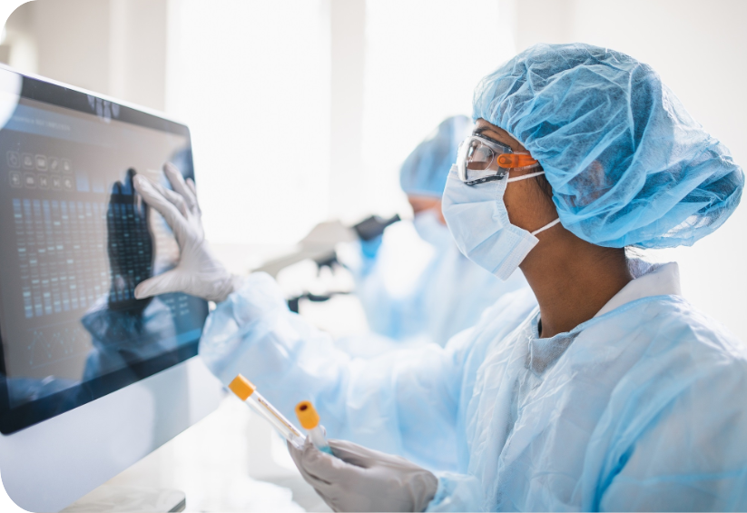 Eine Person in einem Laborkittel und einer Maske mit einem Computer